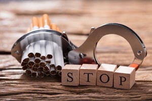 Foto mit Zigaretten in einer Handschelle wo darunter Stopp steht